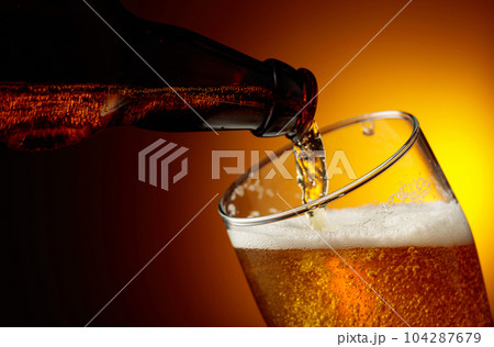 Pouring beer from a bottle into a glass. 104287679