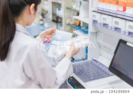薬局・ドラッグストアで自動分包機を使って粉薬・調剤・処方箋を作る薬剤師 薬局・ドラッグストアで自動分包機を使って粉薬・調剤・処方箋を作る薬剤師 104289804