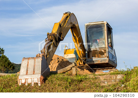 A large construction excavator of yellow color on the construction site 104290310