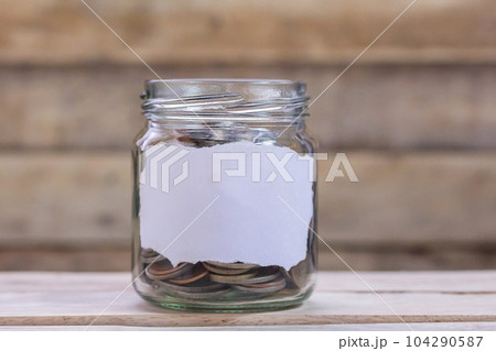 Close up saving money into a glass jar for cash in future investment. Close up saving money into a glass jar for cash in future investment. 104290587