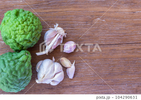 Top view of garlic and bergamot on wood table background with copy space for design. Top view of garlic and bergamot on wood table background with copy space for design. 104290631