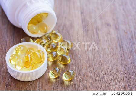 Omega 3 fish liver oil capsules in wooden background. 104290651
