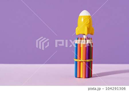 Yellow rocket stands on top of bunch of pencils. purple background. stationery with copy space for back to school or education and creativity concept. Success achievement and innovative ideas 104291306