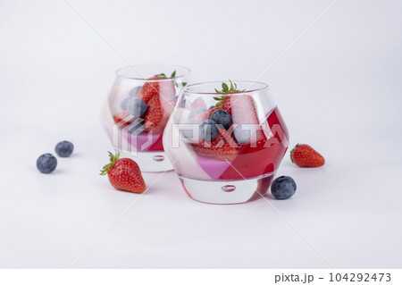 Fruit jelly dessert or panna cotta with fresh strawberries and blueberries, top view, banner, copy space, menu, template for texts on white background. Fruit jelly dessert or panna cotta with fresh strawberries and blueberries, top view, banner, copy space, menu, template for texts on white background. 104292473