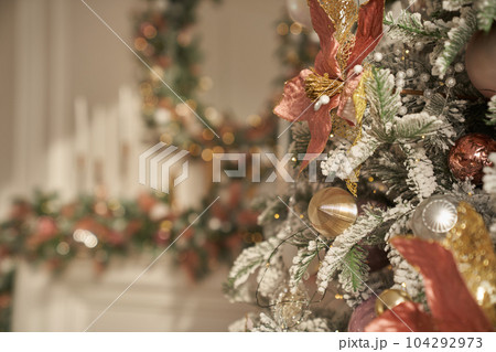 Part of a decorated Christmas tree on the background of a fireplace with a Christmas wreath with space for copying. High quality photo 104292973