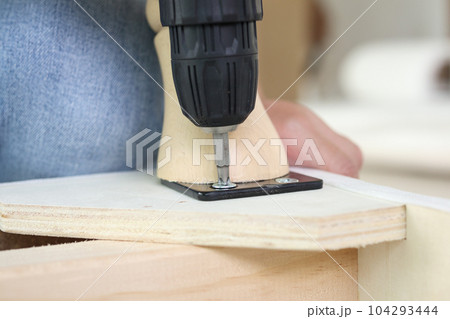 man assembling sofa furniture at home using cordless screwdriver man assembling sofa furniture at home using cordless screwdriver 104293444
