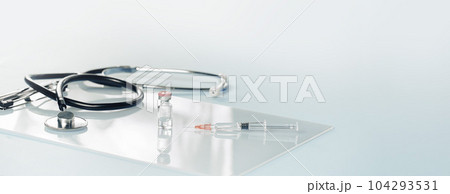 Medical or healthcare concept banner. stethoscope on on a gray desk with a syringe and vial. Vaccination, flu covid rsv jab. Tridemic. Doctor appointment or checkups schedule, PPE. Copy space. Banner 104293531