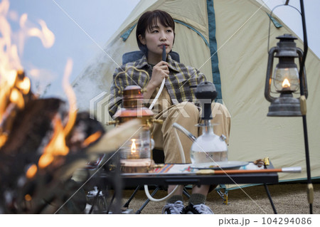 夕方、焚火をしながらで水タバコを吸う若い女性 シーシャ 夕方、焚火をしながらで水タバコを吸う若い女性 シーシャ 104294086