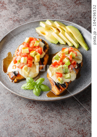 Grilled chicken breast topped with melted cheese, sliced avocado and tomatoes close-up in a plate. Vertical Grilled chicken breast topped with melted cheese, sliced avocado and tomatoes close-up in a plate. Vertical 104296532