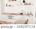 modern kitchen interior in apartment. trendy minimal style furniture with natural wood elements. white kitchen with decor, uncluttered and neat. 104297114