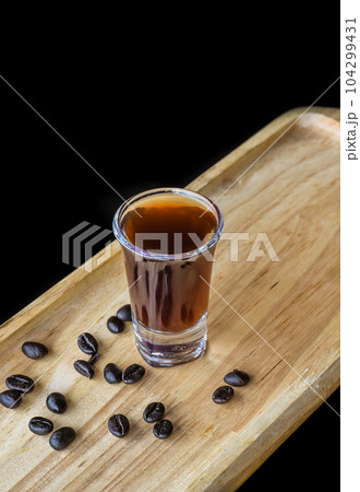 Alcohol shot made of coffee on wooden board with coffee beans with copy space Alcohol shot made of coffee on wooden board with coffee beans with copy space 104299431