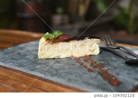 Burnt cheesecake on a stone plate with mint leaf 104302128