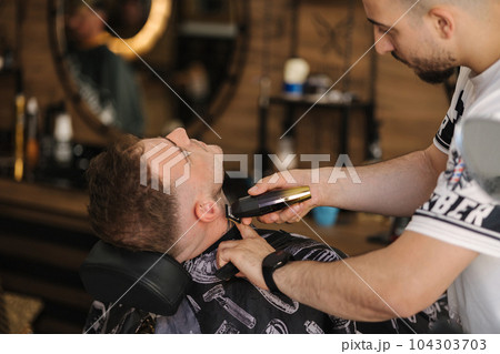 Rear view shot of hairdresser cutting hair of male client. Barber shop Rear view shot of hairdresser cutting hair of male client. Barber shop 104303703