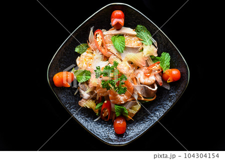 Thai salad made of shrimps and squid and onions isolated on black background top view Thai salad made of shrimps and squid and onions isolated on black background top view 104304154