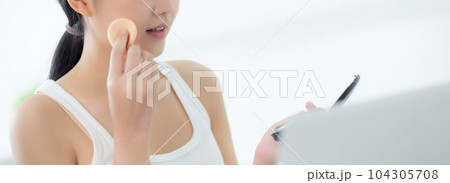 Beauty of young asian woman with learning makeup with powder puff on cheek watching laptop. Beauty of young asian woman with learning makeup with powder puff on cheek watching laptop. 104305708