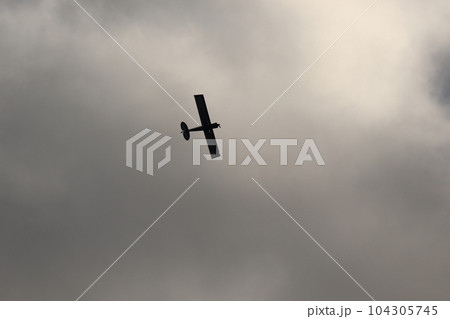 Small plane flying in the sky against dark clouds Small plane flying in the sky against dark clouds 104305745