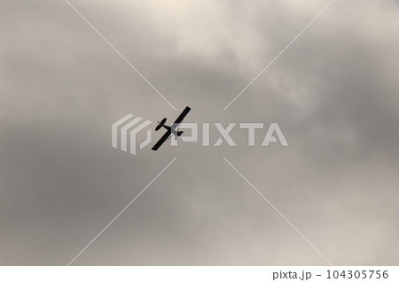 Small plane flying in the sky against dark clouds Small plane flying in the sky against dark clouds 104305756