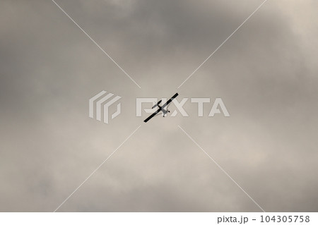 Small plane flying in the sky against dark clouds Small plane flying in the sky against dark clouds 104305758