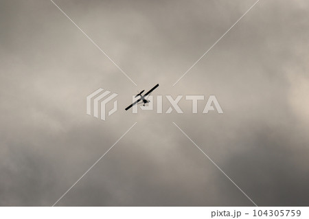 Small plane flying in the sky against dark clouds Small plane flying in the sky against dark clouds 104305759