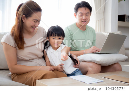 Happy family with mother teaching homework with daughter and father working with laptop on sofa. Happy family with mother teaching homework with daughter and father working with laptop on sofa. 104305774