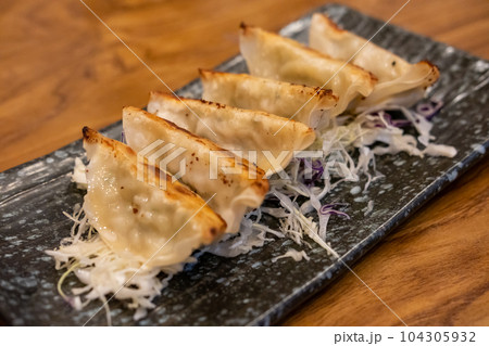 Gyoza served on a plate with vegetable on the table Gyoza served on a plate with vegetable on the table 104305932