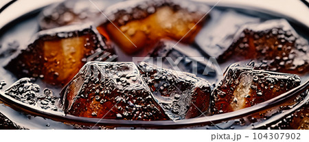 Cola with Ice. Close up of the ice cubes in cola water. Texture of carbonate drink with bubbles in glass. Cola soda and ice splashing fizzing or floating up to top of surface. Cold drink background. Cola with Ice. Close up of the ice cubes in cola water. Texture of carbonate drink with bubbles in glass. Cola soda and ice splashing fizzing or floating up to top of surface. Cold drink background. 104307902