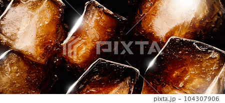 Cola with Ice. Close up of the ice cubes in cola water. Texture of carbonate drink with bubbles in glass. Cola soda and ice splashing fizzing or floating up to top of surface. Cold drink background. 104307906