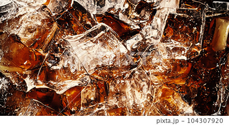 Cola with Ice. Close up of the ice cubes in cola water. Texture of carbonate drink with bubbles in glass. Cola soda and ice splashing fizzing or floating up to top of surface. Cold drink background. Cola with Ice. Close up of the ice cubes in cola water. Texture of carbonate drink with bubbles in glass. Cola soda and ice splashing fizzing or floating up to top of surface. Cold drink background. 104307920