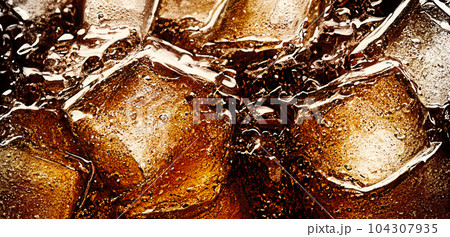 Cola with Ice. Close up of the ice cubes in cola water. Texture of carbonate drink with bubbles in glass. Cola soda and ice splashing fizzing or floating up to top of surface. Cold drink background. 104307935