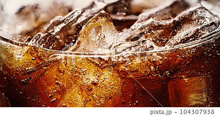 Cola with Ice. Close up of the ice cubes in cola water. Texture of carbonate drink with bubbles in glass. Cola soda and ice splashing fizzing or floating up to top of surface. Cold drink background. Cola with Ice. Close up of the ice cubes in cola water. Texture of carbonate drink with bubbles in glass. Cola soda and ice splashing fizzing or floating up to top of surface. Cold drink background. 104307938