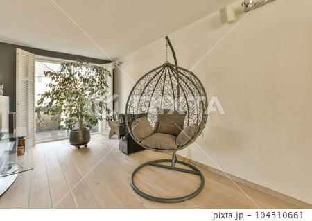 a living room with a hanging chair in the middle and a tv on the right side, next to an open door a living room with a hanging chair in the middle and a tv on the right side, next to an open door 104310661