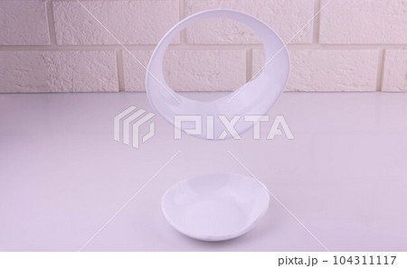 Fragments of a broken white plate flying on a white background Fragments of a broken white plate flying on a white background 104311117