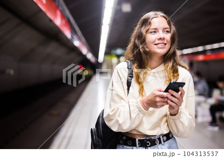 Positive girl in the subway, texting on a mobile phone with friends 104313537