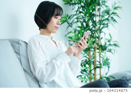 ソファに座ってスマートフォンを操作する女性 104314875