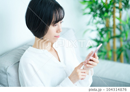 ソファに座ってスマートフォンを操作する女性 104314876