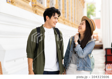 Portrait of Asian man and woman travel couple backpackers in relationship inside of buddhist temple on the street in Bangkok, Thailand, Southeast Asia - carefree and happy traveling concept 104315606