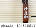 店頭のシャッター前に吊り下げられた木製の支度中の札看板 104316611