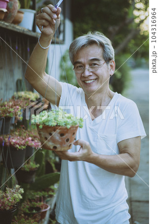 asian holding hanging houseplant pot toothy smiling with happiness face standing outdoor asian holding hanging houseplant pot toothy smiling with happiness face standing outdoor 104316964