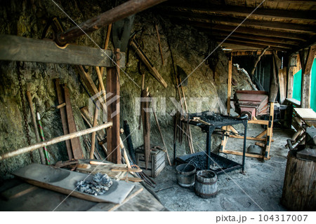 View of traditional blacksmith's shop for forging medieval iron, with furnace and an ancient bellows blower 104317007
