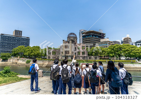 原爆ドームを訪れたボランティアガイドの説明に聞き入る修学旅行生 104318327