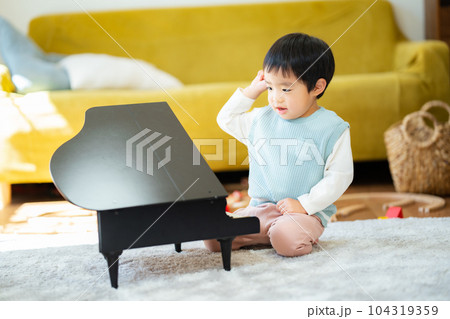 リビングでおもちゃのピアノを弾く3歳の男の子 リビングでおもちゃのピアノを弾く3歳の男の子 104319359