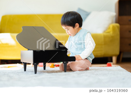 リビングでおもちゃのピアノを弾く3歳の男の子 104319360