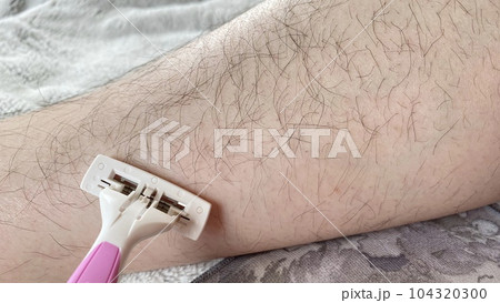 ピンク色の使い捨てカミソリで足のムダ毛を処理する女性 ピンク色の使い捨てカミソリで足のムダ毛を処理する女性 104320300