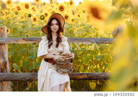 Beautiful woman in a dress in a field of sunflowers 104320502
