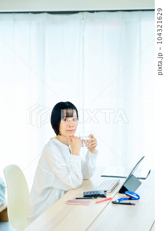 部屋でのパソコン作業中に一息入れる女性 104321629