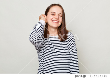 Happy face. Positive emotions. Smiling attractive cheerful brown haired woman wearing striped shirt posing isolated over gray background Happy face. Positive emotions. Smiling attractive cheerful brown haired woman wearing striped shirt posing isolated over gray background 104323740