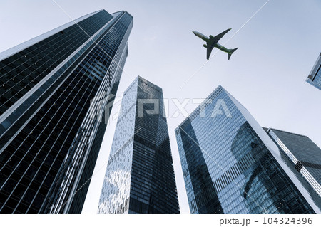 Airplane flying on business skyscrapers of financial center. Travel, economy, cargo, transportation concept Airplane flying on business skyscrapers of financial center. Travel, economy, cargo, transportation concept 104324396