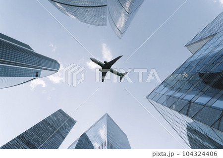 Airplane flying on business skyscrapers of financial center. Travel, economy, cargo, transportation concept 104324406
