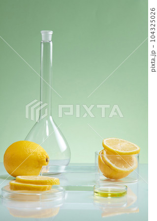 Laboratory concept with glassware containing lemon slices. Empty podium for cosmetic promotion. Lemon (Citrus limon) is very useful to enhance skin condition 104325026