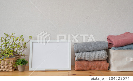 たたまれた冬物の服と白いフレーム|洗濯物・衣替えイメージ たたまれた冬物の服と白いフレーム|洗濯物・衣替えイメージ 104325074